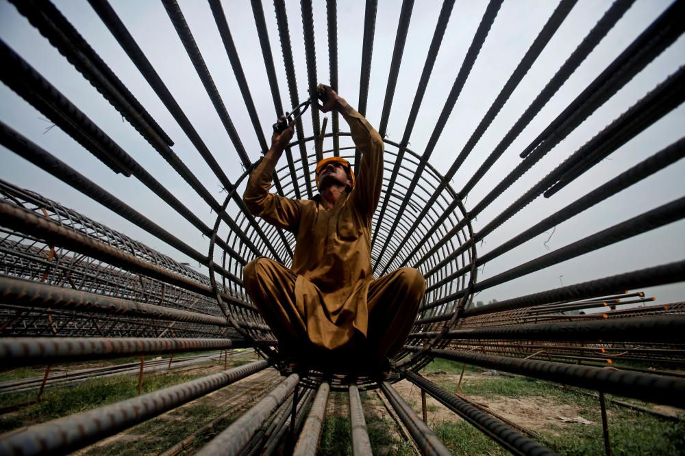 A worker ties steel bars at a construction site ...