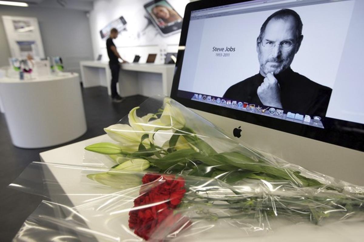 Flores colocadas frente a una pantalla con la fotografía de Steve Jobs, en una tienda de la marca en Moscú (Rusia).