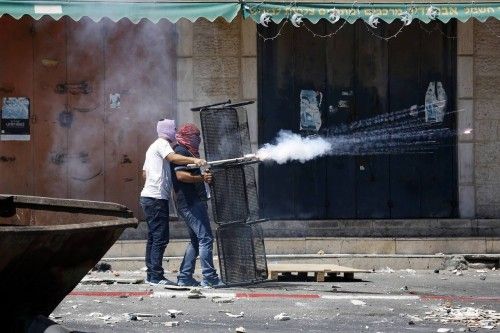 Palestinos lanzan petardos hacia la policía israelí durante los enfrentamientos en Shuafat, un barrio árabe de Jerusalén.