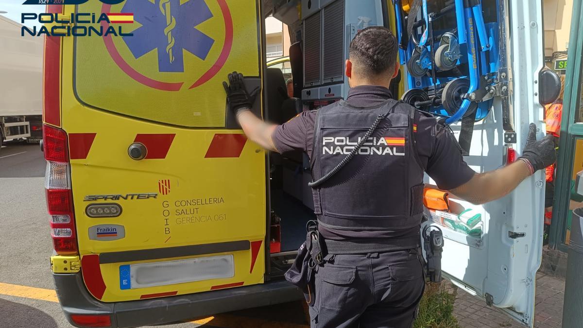Un agente de la Policía Nacional, junto a una ambulancia.