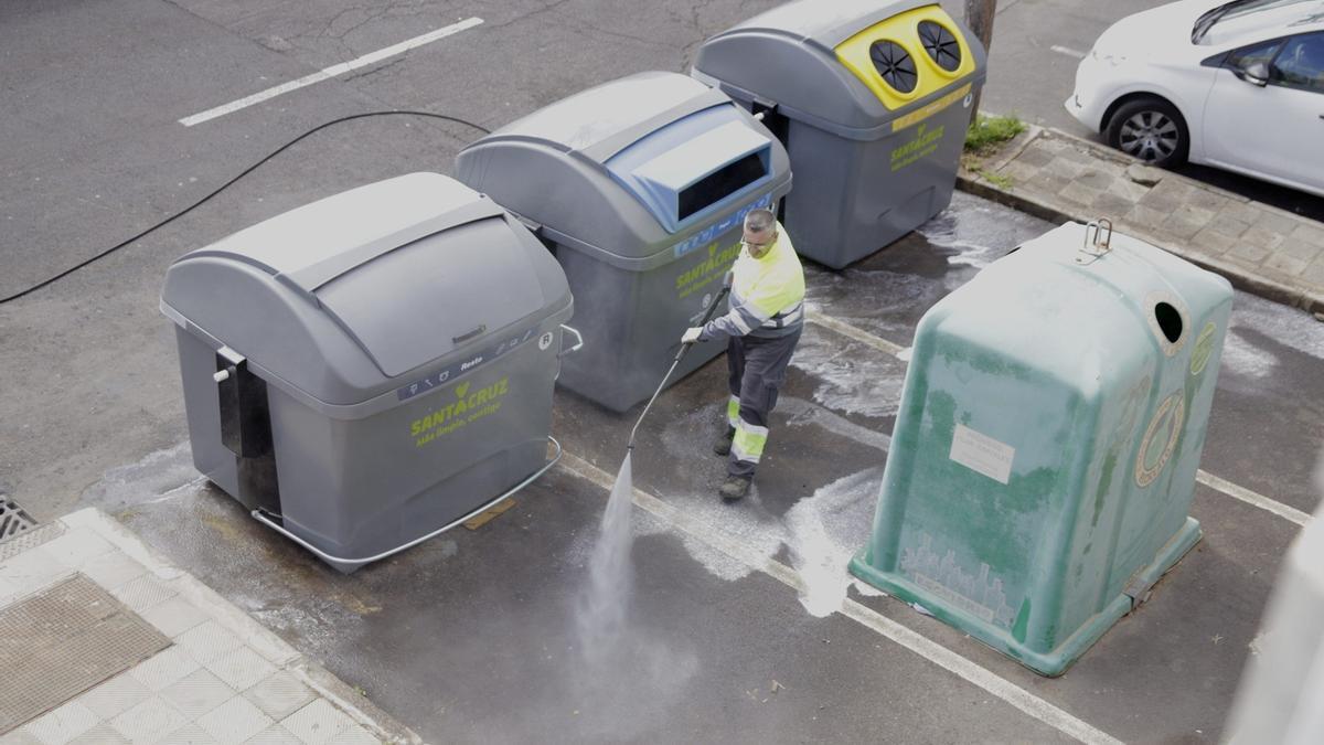 Trabajadores limpiando contenedores entre ellos verdes destinados al vidrio