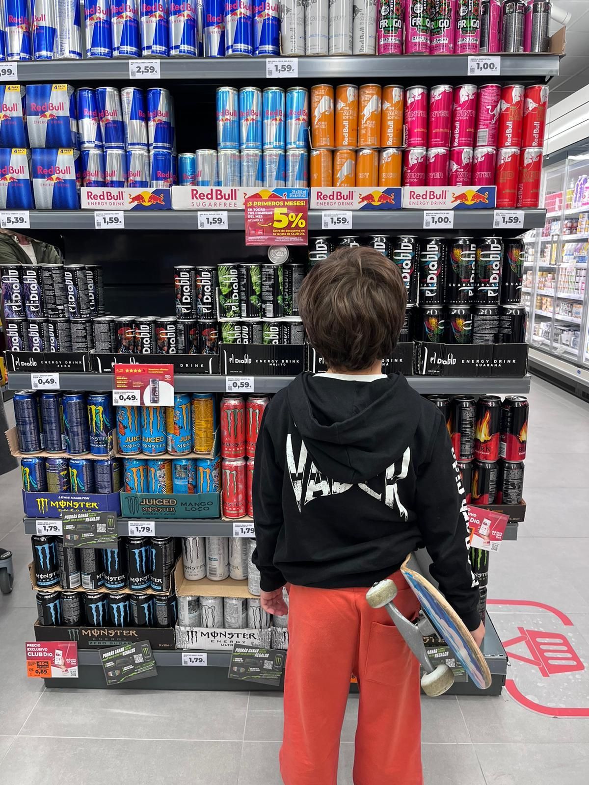 Un menor observa bebidas energéticas en un supermercado.