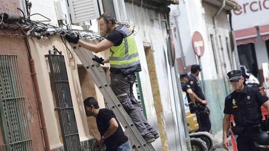 Un policía examina el cableado en una casa allanada.