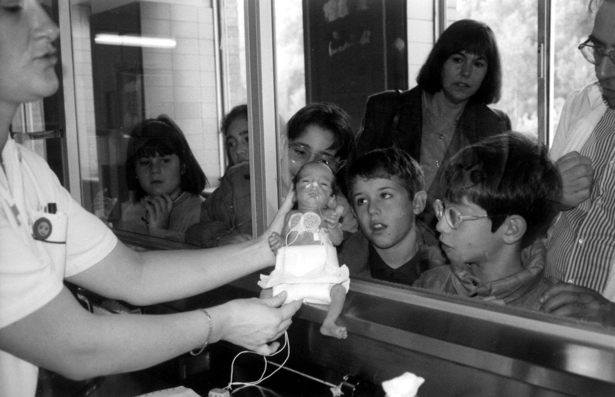 Una infermera mostra un nounat a escolars, que estan de visita al centre.