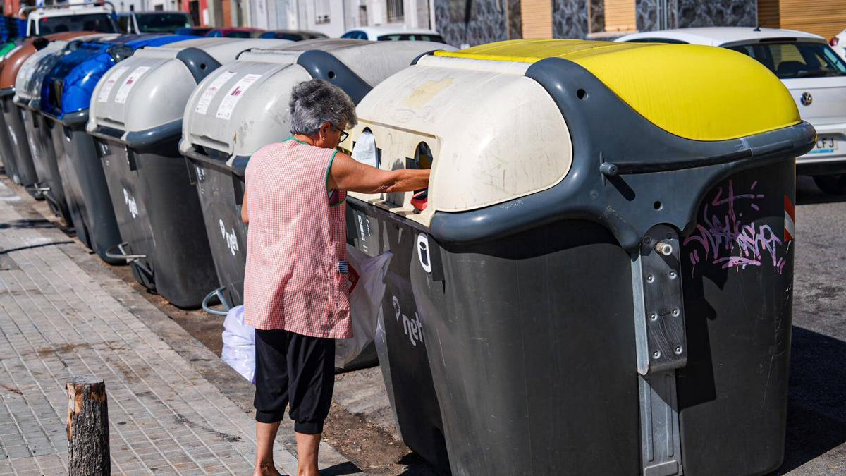 Una mujer tirando la basura en un contenedor.