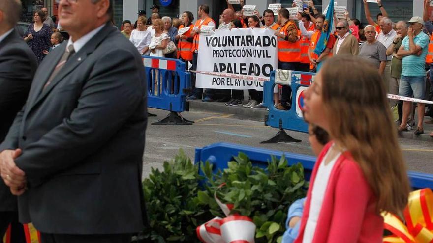 Una veintena de voluntarios de Protección Civil, al fondo, durante la protesta en el acto de la ofrenda floral a Jovellanos.