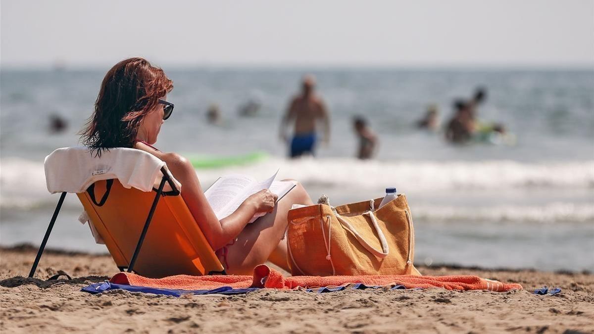 Una mujer leyendo en la playa.