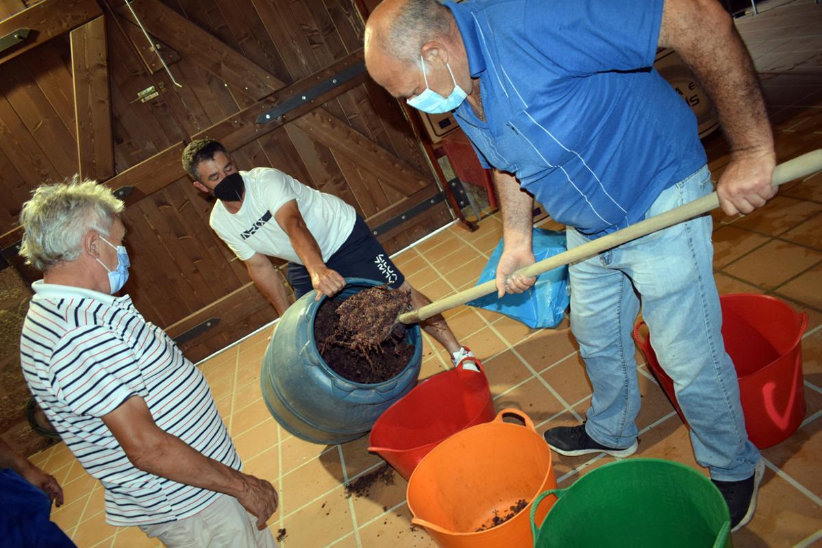 Los "poteiros" extraen el bagazo de un bidón de plástico, paso previo a la destilación
