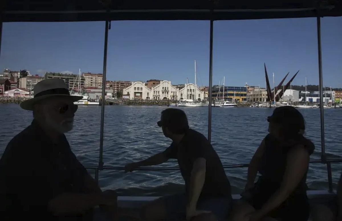 Asistentes a la excursión, en el barco, con Avilés al fondo. | NICO RODRÍGUEZ