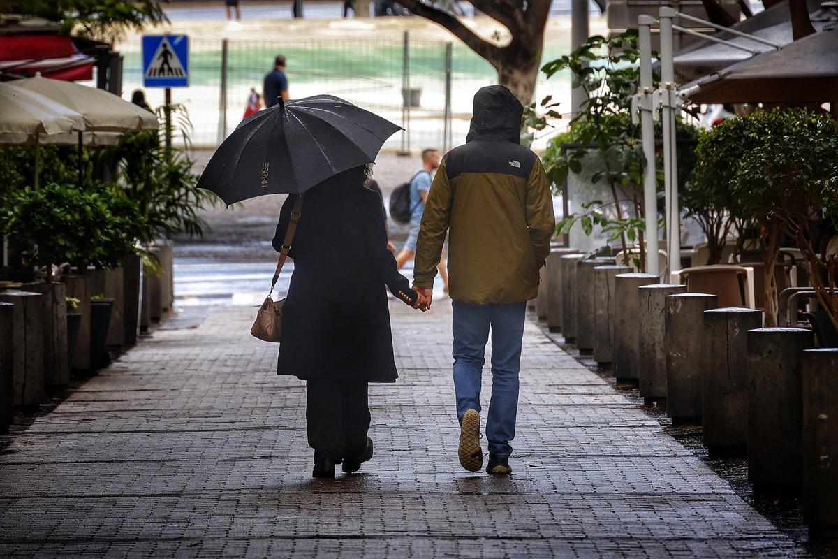 Una pareja pasea bajo la lluvia en Santa Cruz de Tenerife.