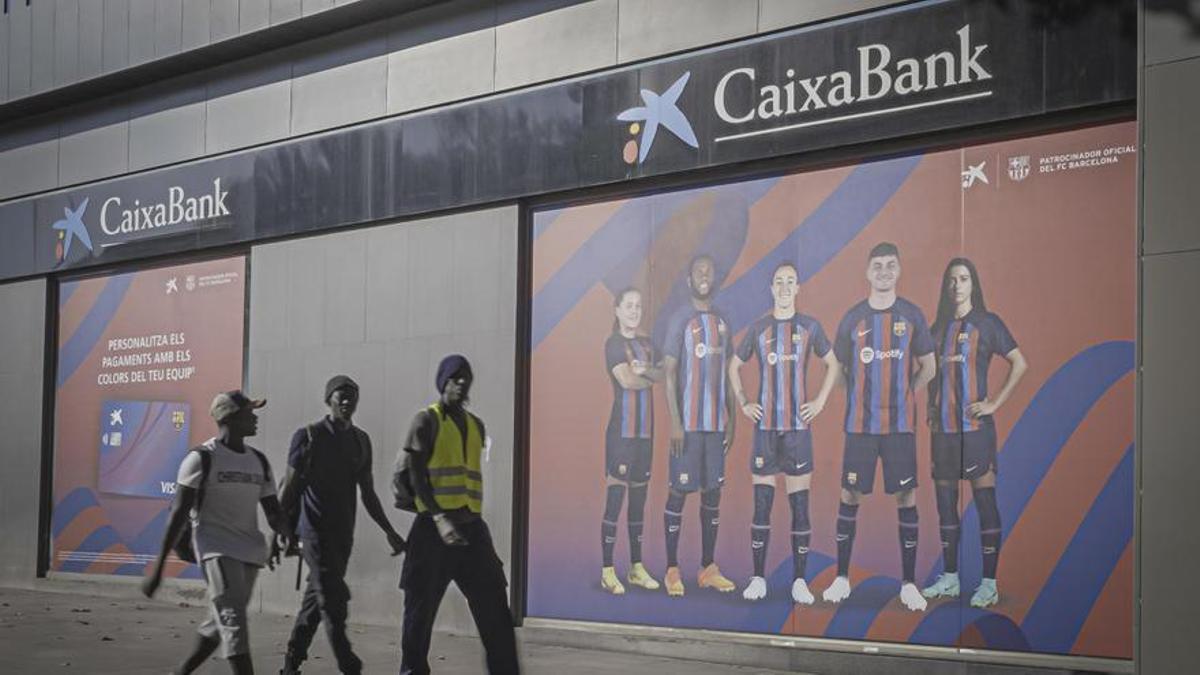 Obreros pasan por delante de un cartel publicitario con los jugadores del Barça.