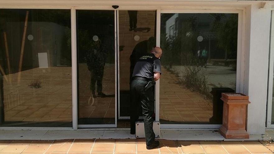 Un agente de la Guardia Civil inspecciona una de las puertas de acceso forzadas.