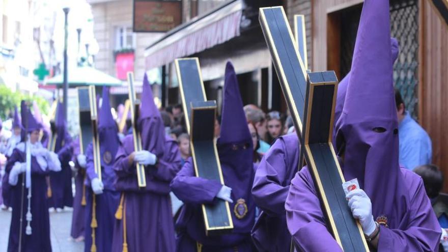 Nazarenos portan sus cruces en Viernes Santo por la mañana en Murcia.