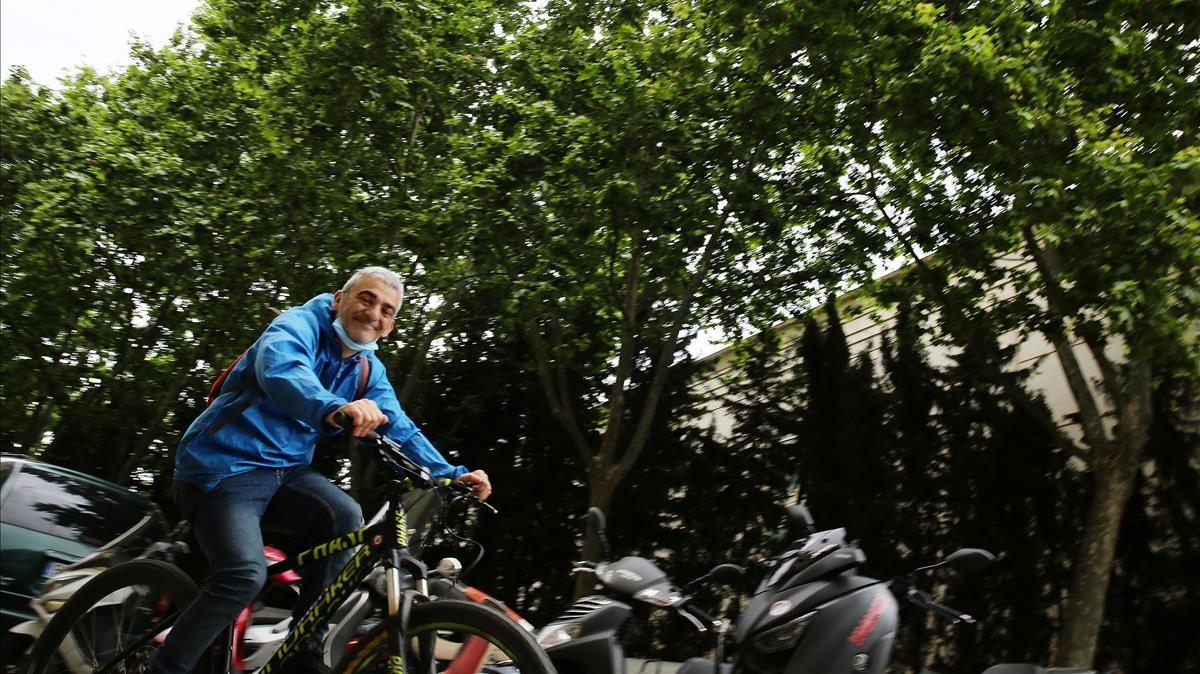 Un ciclista pasa por delante de una frondosa y, en primavera, irritante hilera de plátanos de Barcelona