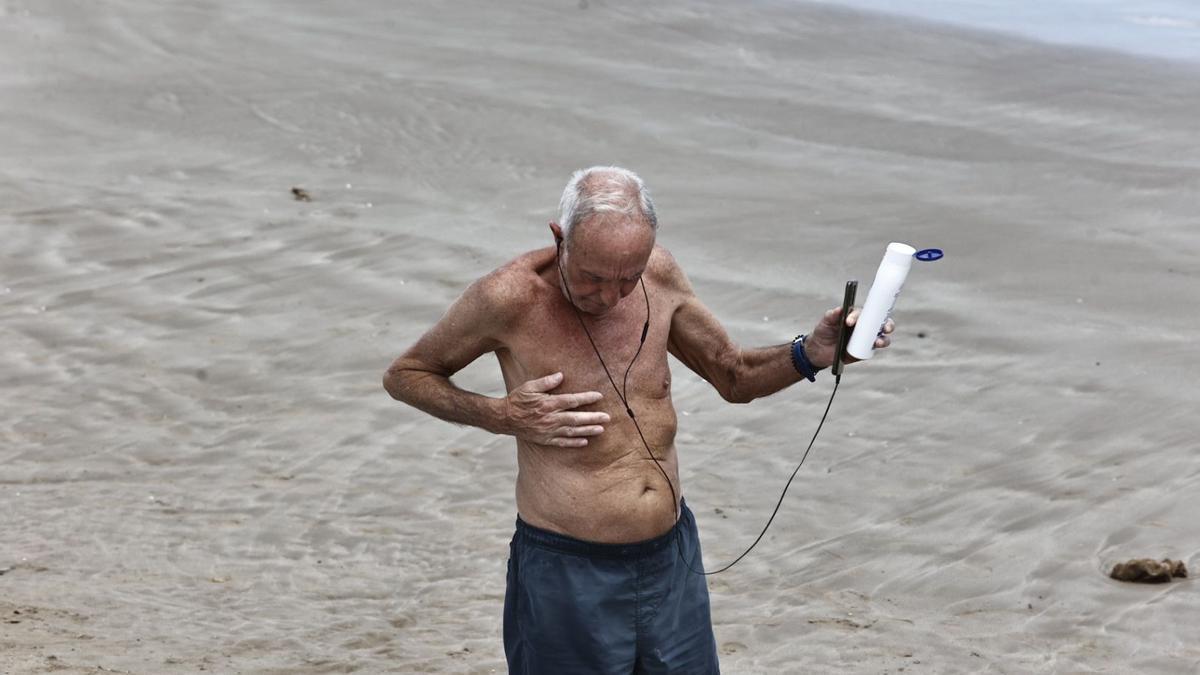 Un hombre se impregna loción protectora en la playa de la Malva-rosa de València.