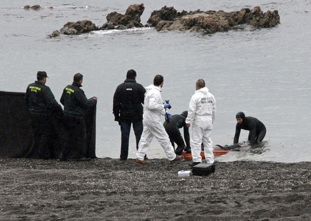 Agents de la Guàrdia Civil retiren el cos del subsaharià trobat avui a la platja del Tarajal de Ceuta.