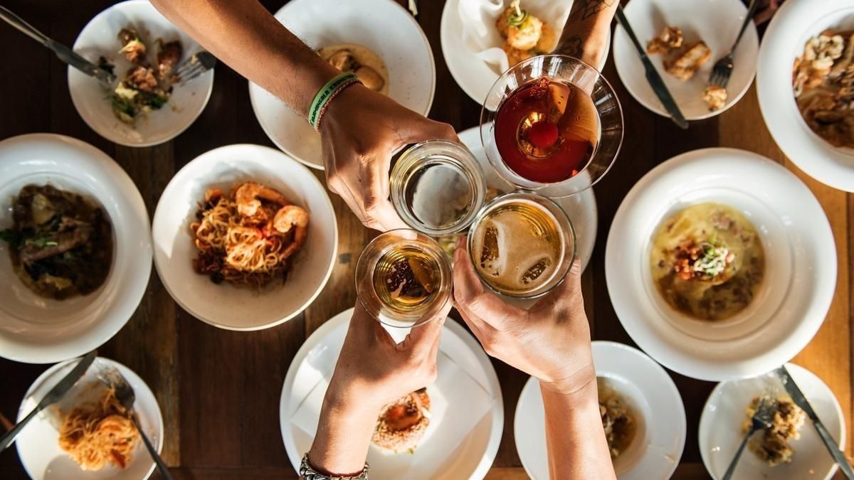 Cuatro personas brindan sobre una mesa llena de tapas.