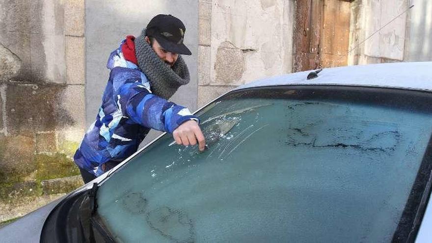 Un hombre retira la capa de hielo del coche, ayer en Maside.  // Iñaki Osorio