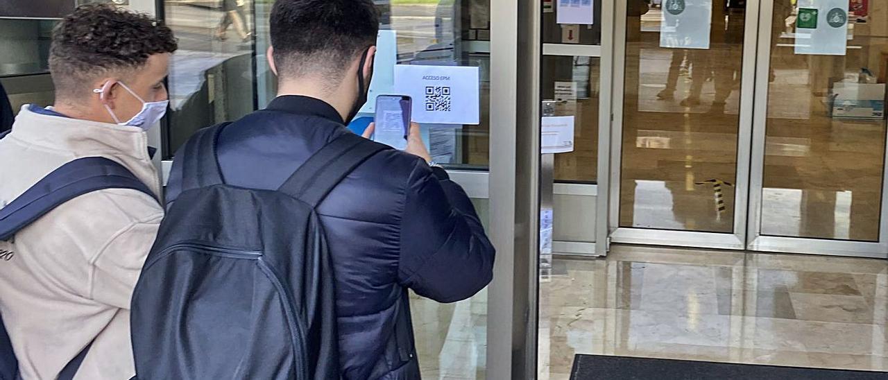 Dos alumnos utilizan la aplicación con el código QR a la entrada del centro. | Vivas