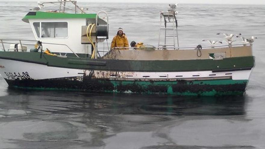 La embarcación del patrón mayor, «Abelán», el día del vertido, rodeada por una mancha de fuel.