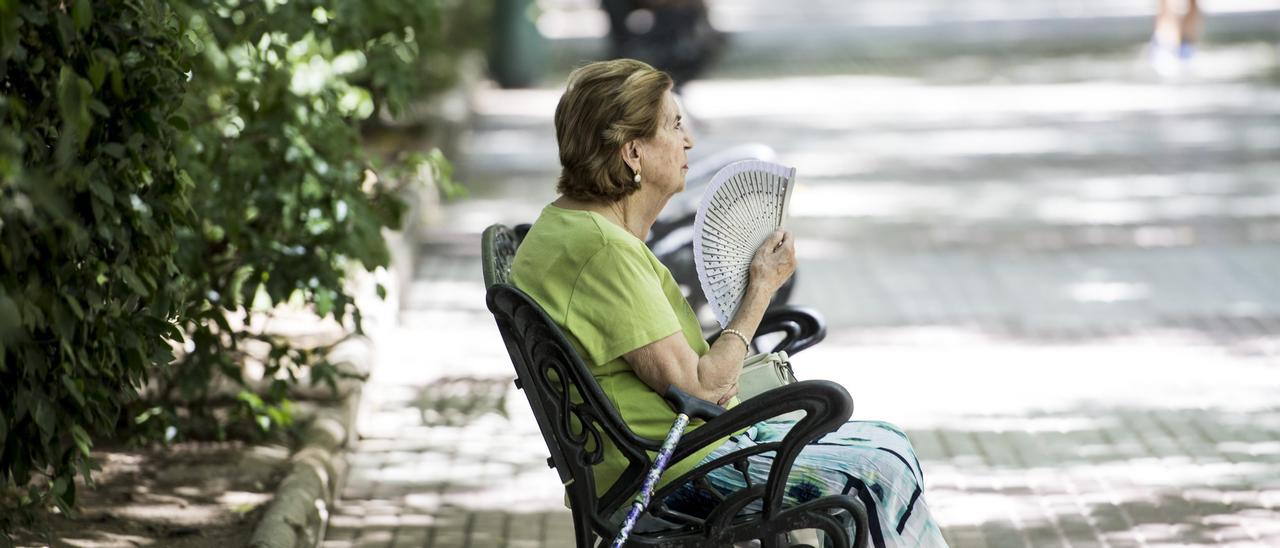 Una mujer se abanica para sofocar las altas temperaturas sentada en un banco del paseo de Cánovas de Cáceres.