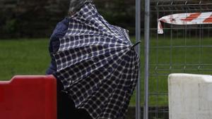 Una persona se protege de la lluvia y el viento en una calle de Lugo este jueves.