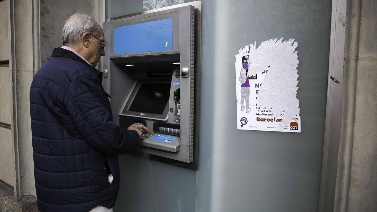 Un pensionista saca dinero de un cajero automático de una entidad bancaria de Barcelona, el 1 de marzo del 2019