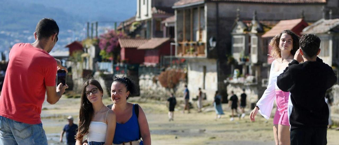 Varios turistas se fotografían ante una estampa típica de Combarro.