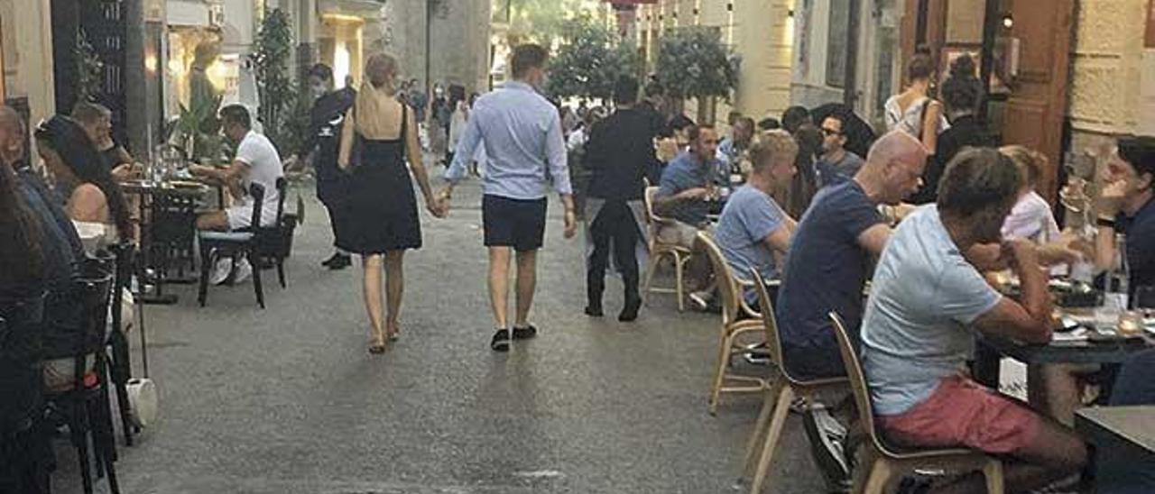 Imagen de la calle Sant Joan ocupada con mesas y sillas pegadas a la fachada de los establecimientos.