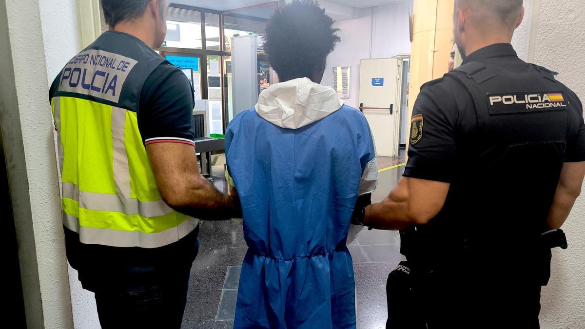 El detenido por intento de homicidio, custodiado por dos agentes en la Jefatura de Policía.