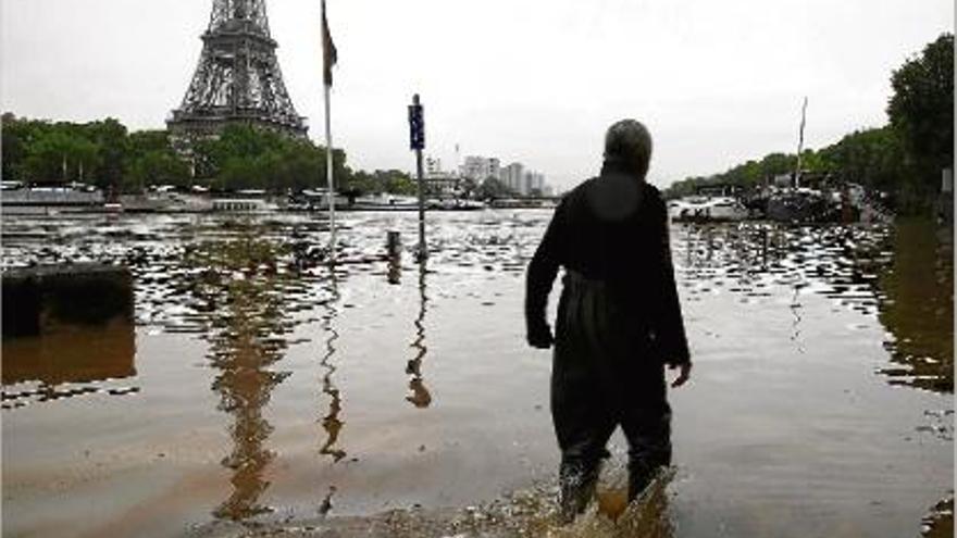 Un home camina per una zona totalment inundada propera a la torre Eiffel.