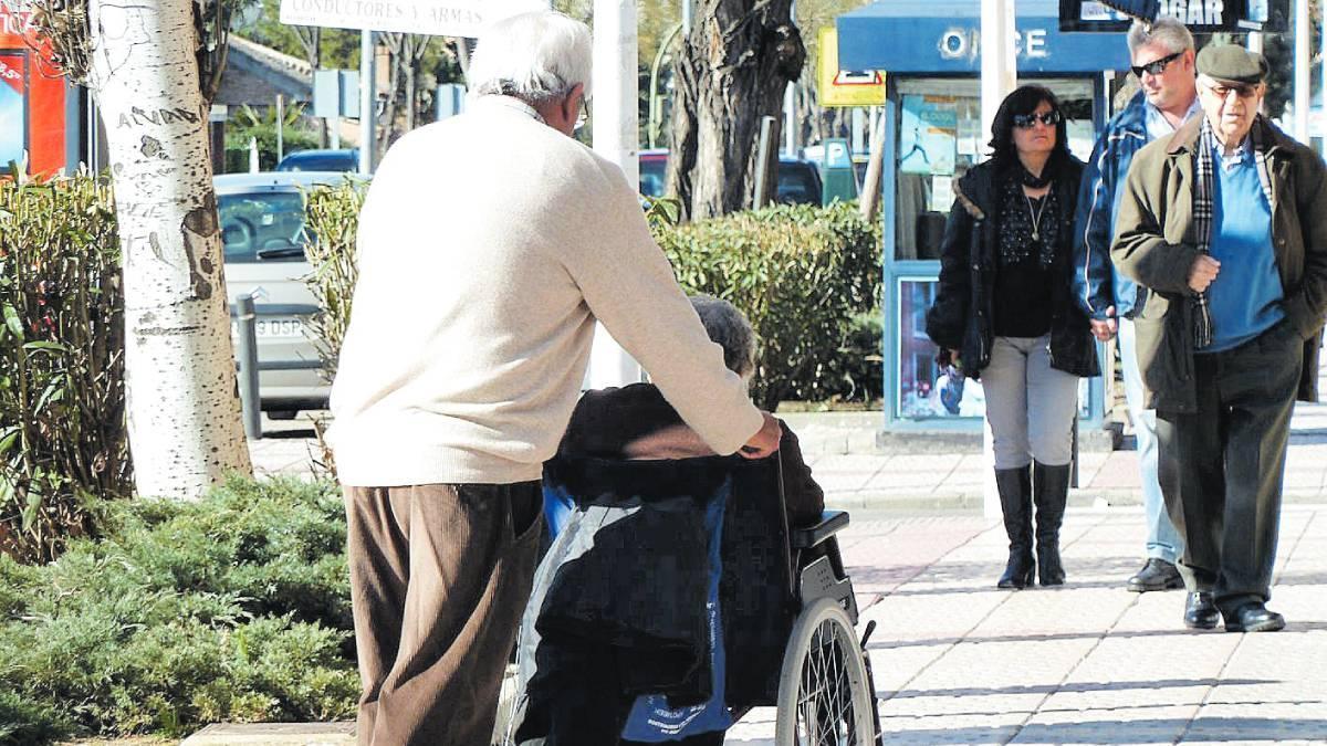 Un hombre mayor ayuda a una mujer en silla de ruedas