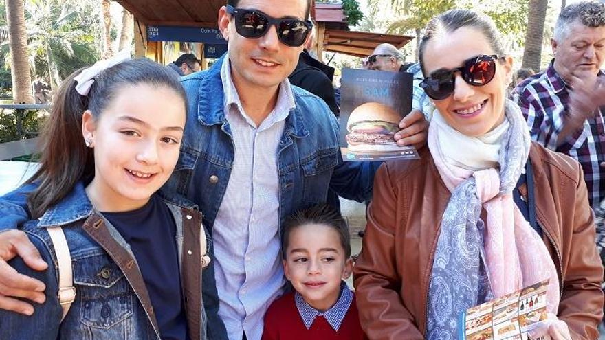 Una familia, con el folleto del menú alternativo en la Feria de Sabor a Málaga.