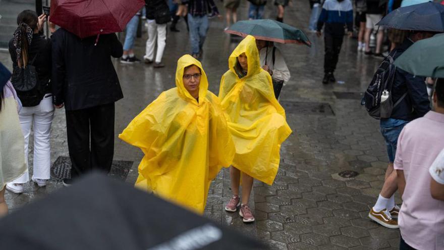 Uns turistes es protegeixen de la pluja, ahir a Barcelona. | ZOWY VOETEN