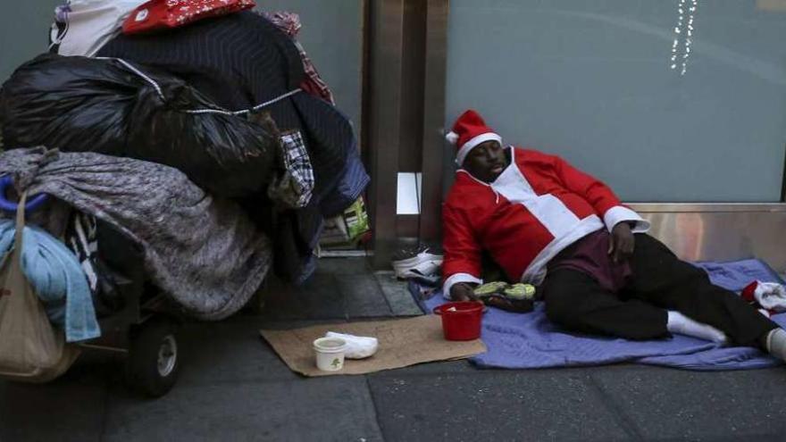 Un hombre vestido de Santa Claus duerme en la calle. // Efe