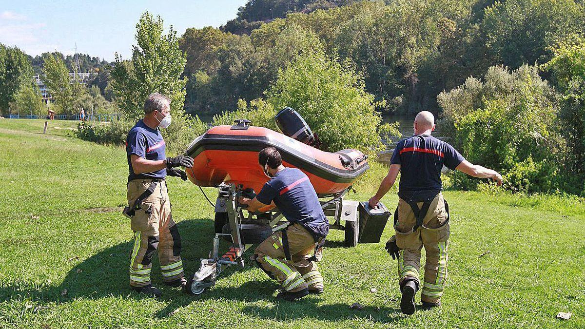 Los bomberos recogen la lancha tras rescatar el cuerpo en el Miño en Oira.