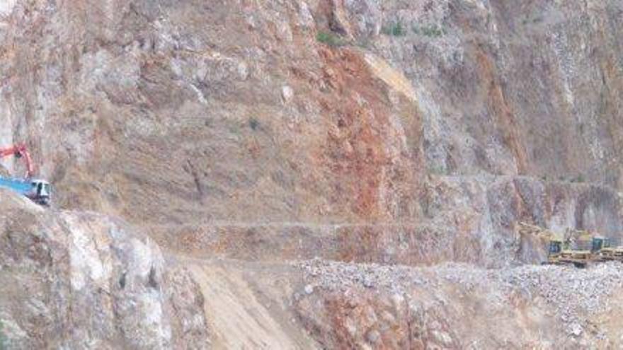 Una excavadora y un camión trabajan frente a una de las paredes de la cantera de ses Planes.