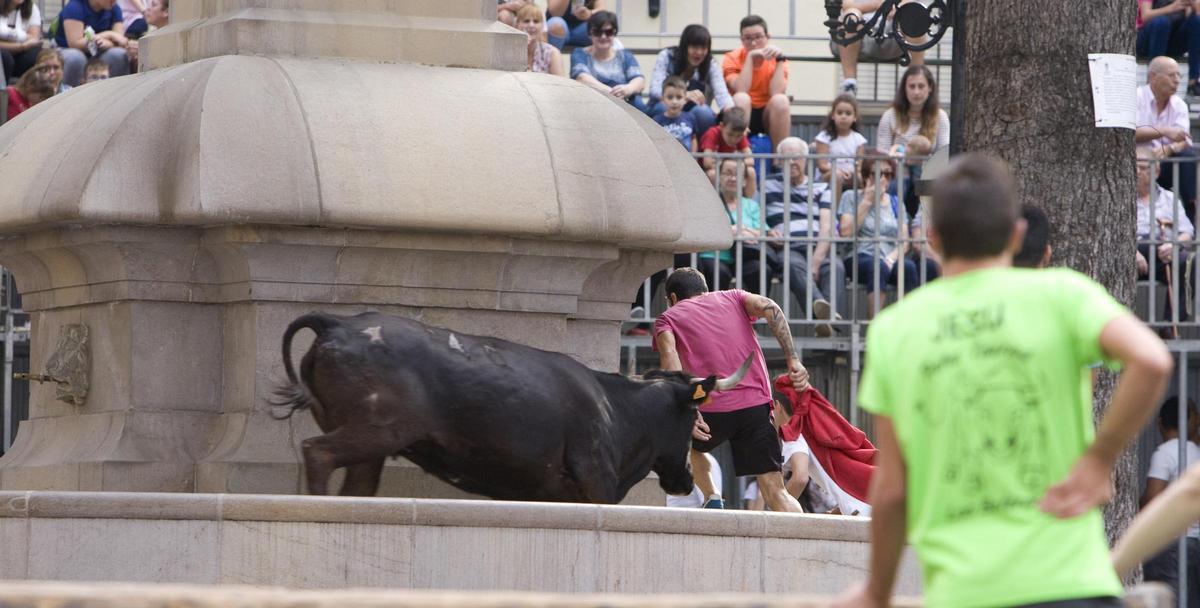 Un toro sube a la fuente de la plaza principal de Enguera en els «bous al carrer».