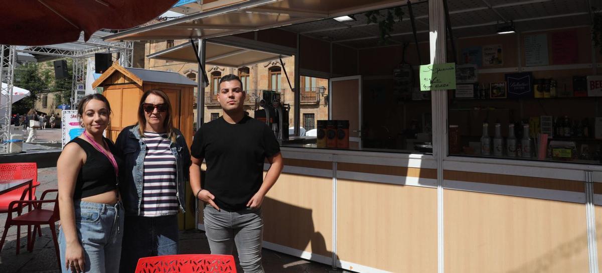 Por la izquierda, Yadhira Antuña, Clara María Iglesias y Gorka Muñiz posan frente a su caseta en la plaza de la Catedral. | Luisma Murias