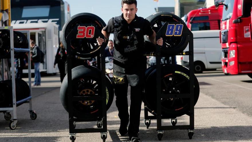 Un operario transporta varios neumáticos en el paddock hoy.