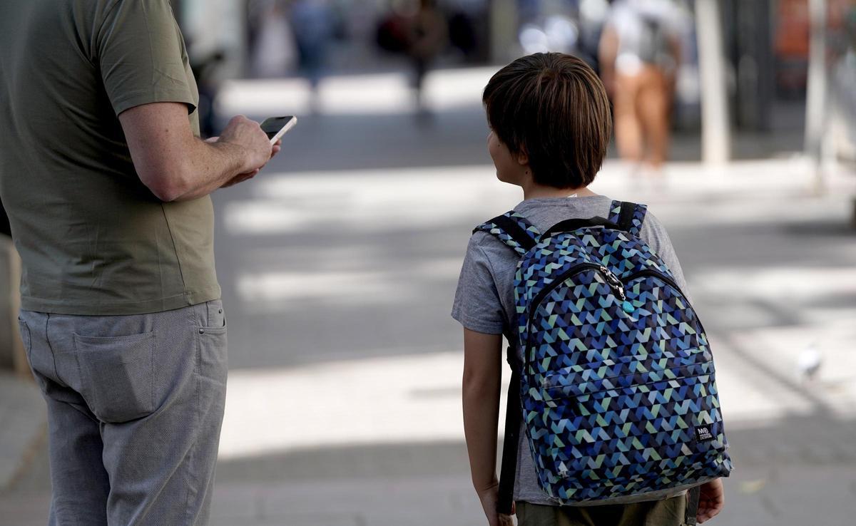 Un padre chatea con su móvil, a la salida del colegio.