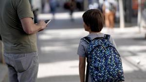 Un padre chatea con su móvil, a la salida del colegio.