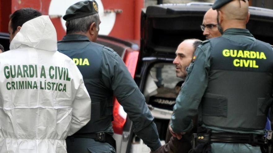 Javier Ledo, rodeado de guardias civiles, durante el registro de su casa en Navia.