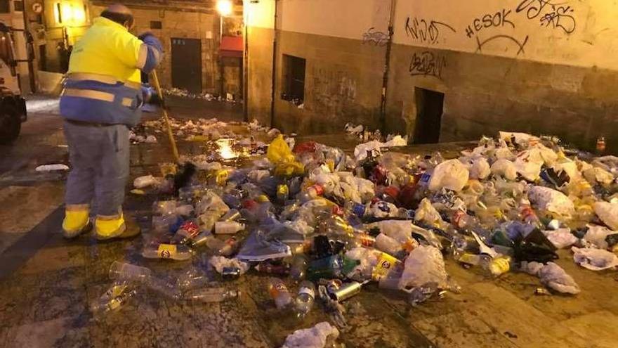 Un trabajador del servicio de limpieza municipal retirando los residuos tras un botellón en el Antiguo.