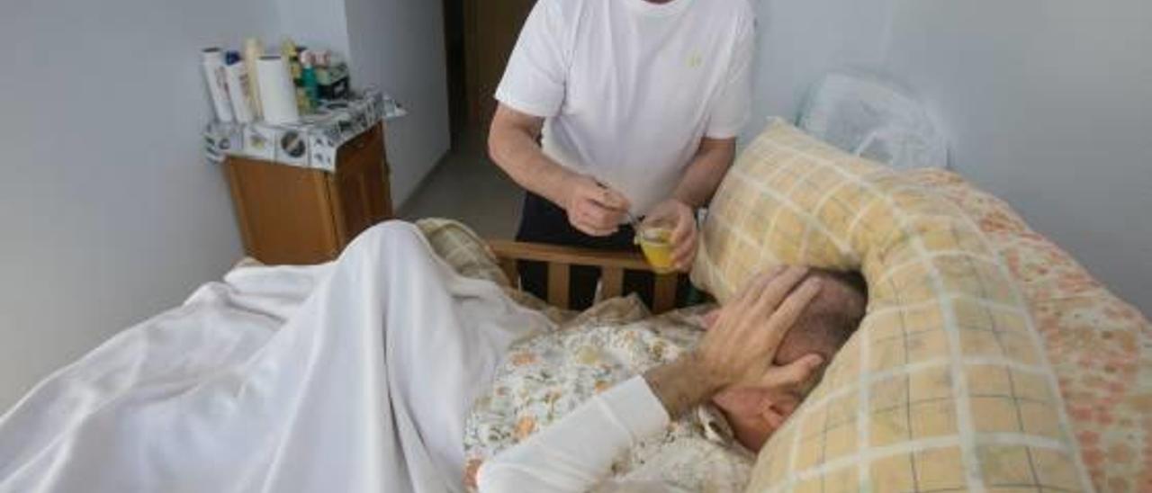 Un cuidador atiende a un dependiente en su domicilio.