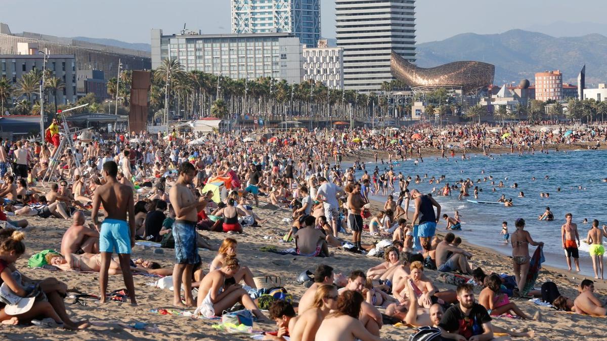 Muchísimos turistas disfrutan del verano en la plaza de la Barceloneta.