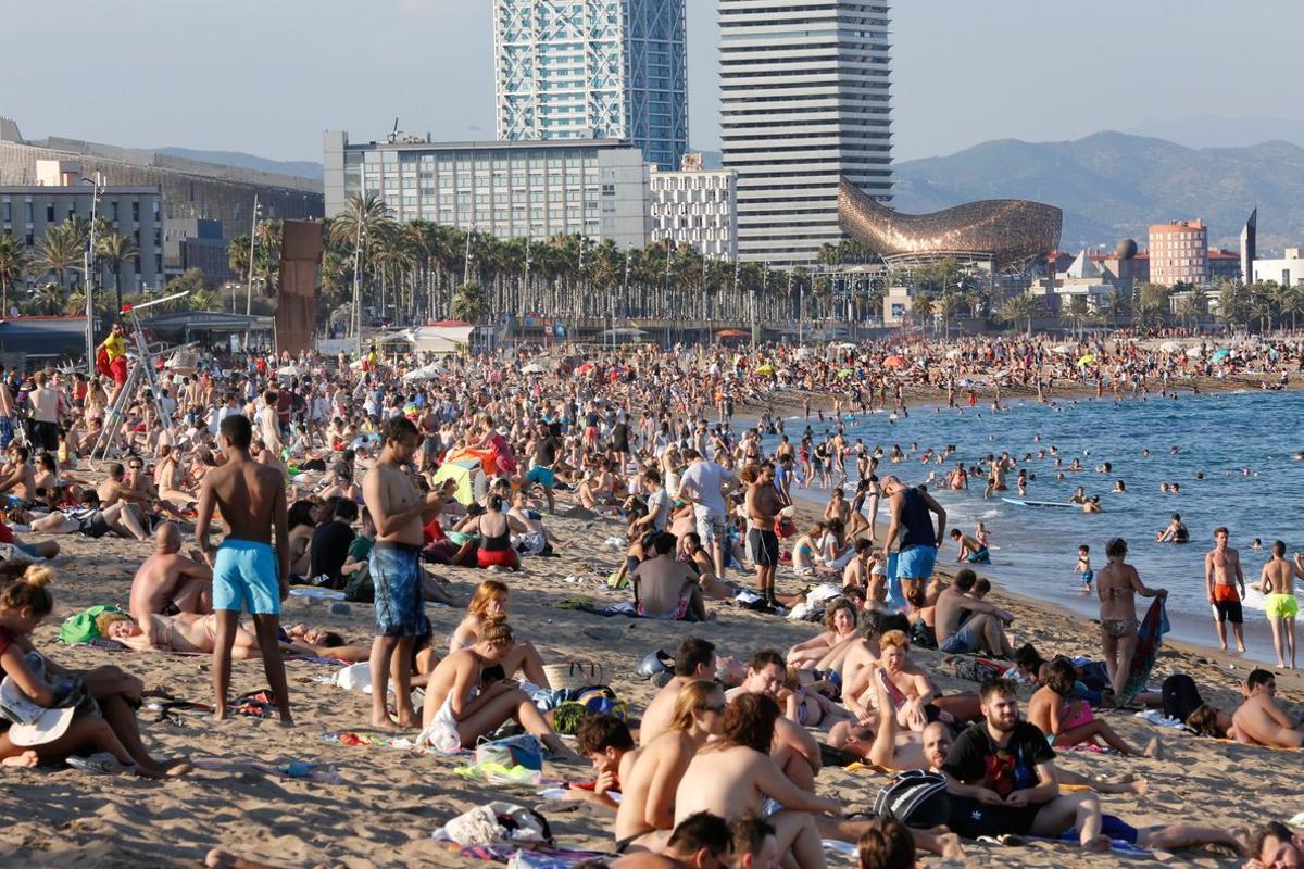 Muchísimos turistas disfrutan del verano en la plaza de la Barceloneta.