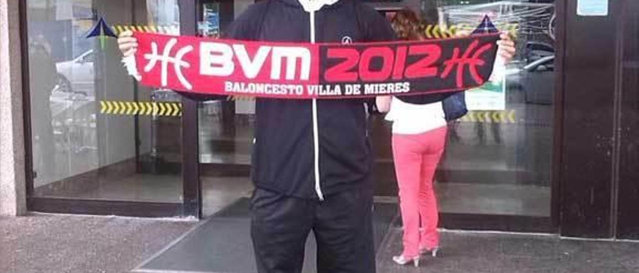 Kevin Tyrone Powell sostiene la bufanda del Villa de Mieres en el aeropuerto de Asturias el día de su llegada.