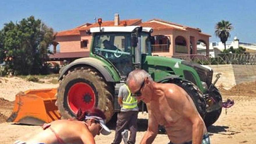 Las máquinas abren una zanja en les Deveses de Dénia con bañistas en la playa