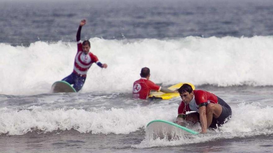 Tres personas practican surf en la playa de San Lorenzo, en Gijón.